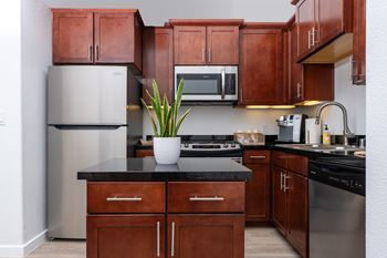 A kitchen with brown cabinets and a black countertop.